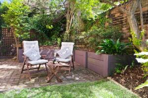 two chairs and a table in a garden at 'Garden Escape' Serene Coastal Living in Wollongong 