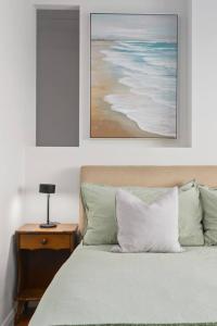 een slaapkamer met een bed en een nachtkastje met een foto bij Rockpool Escape - A Coastal Refresh with Balcony in Shellharbour