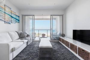 sala de estar con sofá y TV de pantalla plana en Bonbeach Bliss - Contemporary Waterfront Living, en Bonbeach