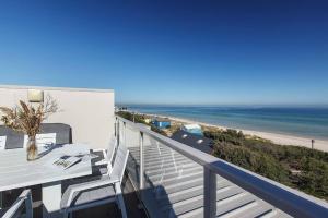 a balcony with a table and a view of the beach at Bonbeach Bliss - Contemporary Waterfront Living in Melbourne
