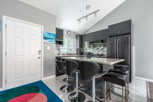 a kitchen with black cabinets and black bar stools at Stylish Dual Bedroom Suite in Van West in Vancouver