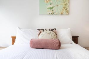 Una cama blanca con una almohada rosa. en 'Seaford Sands' Beachfront at Port Phillip Bay, en Seaford