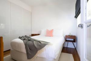 a bedroom with a white bed with a pink pillow at Couples Corner - A Stylish Bay View Retreat in McCrae