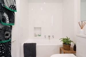 a white bathroom with a tub and a plant at Couples Corner - A Stylish Bay View Retreat in McCrae +16 photos