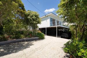 a white house with a balcony and a driveway at Couples Corner - A Stylish Bay View Retreat in McCrae