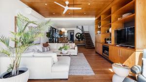 a living room with white couches and a tv at The Boathouse on the Beach in Corlette