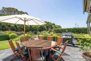 a wooden table with chairs and an umbrella at Viewbank Homestead - A Sprawling Garden Estate in Shoreham