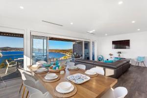 a living room with a couch and a table and chairs at Bluewater Splendour - Heated infinity pool and amazing views!! in Salamander Bay