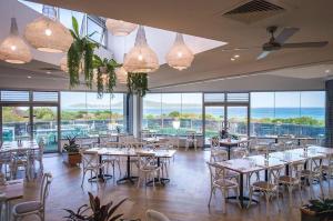 a dining room with tables and chairs and windows at Bluewater Splendour - Heated infinity pool and amazing views!! in Salamander Bay