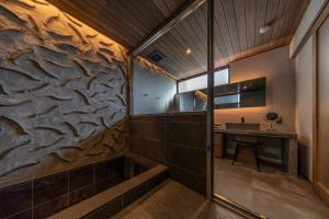 baño con pared de piedra y lavabo en 媛邸【ＥＮＴＥＩ】, en Matsuyama