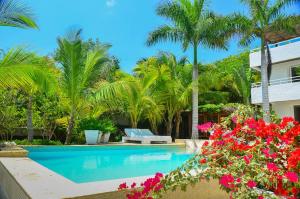 a resort swimming pool with palm trees and pink flowers at Villa Los Cocos Baru in Barú +48 photos