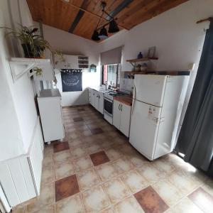 cocina con electrodomésticos blancos y suelo de baldosa. en OMA- Casa Temporaria en Capilla del Monte