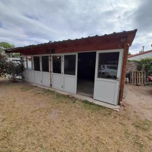 a garage with white doors and a red roof at OMA- Casa Temporaria in Capilla del Monte