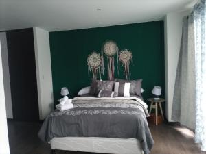 Un dormitorio con una pared de acento verde y una cama en Suite Zen, en Guatemala