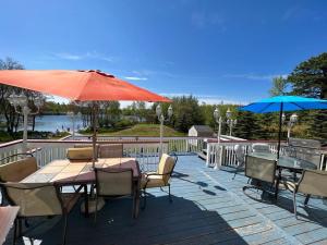 un patio con mesas y sombrillas en una terraza en Stunning Lakefront Home - Swim, Fish, Kayak, HotTub, en Long Pond