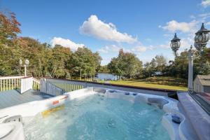 bañera de hidromasaje en una terraza con vistas al lago en Stunning Lakefront Home - Swim, Fish, Kayak, HotTub, en Long Pond