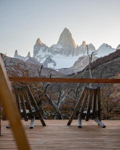 two wooden chairs on a deck with mountains in the background at Estancia Bonanza Patagonian Lodge Experience in El Chalten