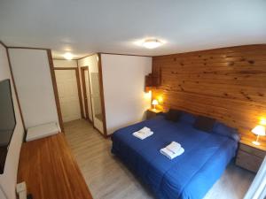 1 dormitorio con 1 cama azul y 2 toallas en Hosteria Lekun Lekun en Villa La Angostura