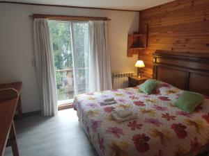 1 dormitorio con cama y ventana en Hosteria Lekun Lekun en Villa La Angostura