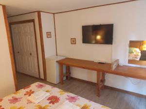 a bedroom with a bed and a desk and a television at Hosteria Lekun Lekun in Villa La Angostura