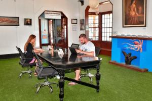 un homme et une femme assis à une table avec un ordinateur portable dans l'établissement La Casona de Lobitos - Cowork, à Lobitos