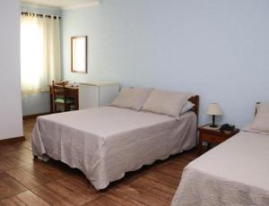 a bedroom with two beds and a desk with a desk at Hotel Estância in Poços de Caldas