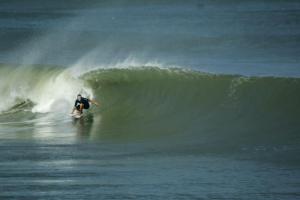 un hombre montando una ola en una tabla de surf en el océano en La Casona de Lobitos - Cowork, en Lobitos