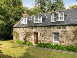 an old stone house with a brown door and windows at South Lodge in Banchory