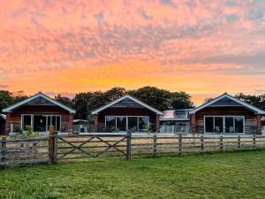 ein Haus hinter einem Zaun mit Sonnenuntergang im Hintergrund in der Unterkunft Cedar Lodge in Old Buckenham