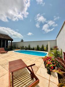 a swimming pool in a yard with a bench and flowers at Noah Hostel & Chale in São Miguel do Gostoso