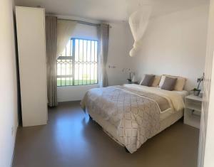 a white bedroom with a bed and a window at Msasa Views Cottage in Juliasdale