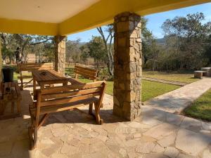 a patio with two wooden benches and a stone pillar at Msasa Views Cottage in Juliasdale