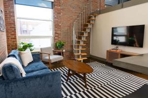 Trendy 1 Br Loft Apt Downtown With Exposed Brick في رونوك: غرفة معيشة مع أريكة زرقاء وتلفزيون