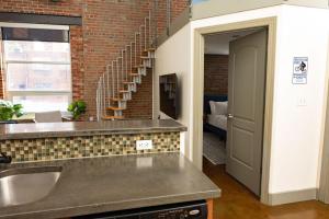 uma cozinha com um lavatório e uma parede de tijolos em Trendy 1 Br Loft Apt Downtown With Exposed Brick em Roanoke