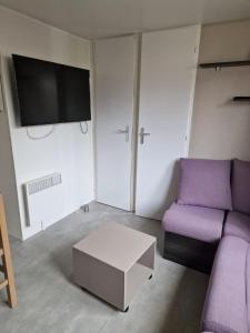 a living room with a purple couch and a tv at Camping Carabasse Vias plage. in Vias