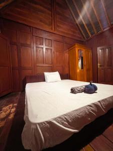 a large bed in a room with wooden walls at Villa Kamar Tamu Bangunjiwo in Ngingas