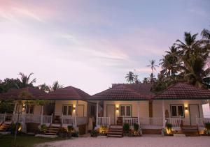 une maison avec une véranda et quelques palmiers dans l'établissement Katiet Beach Resort Mentawai Lances Right HTS, à Katiet