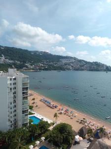a beach with umbrellas and boats in the water at Departamento en Acapulco La Palapa in Acapulco