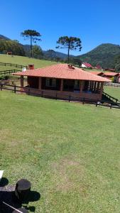 a house with a red roof in a field at Casa de Sítio Rancho crioulo in Urubici