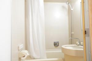 ein Badezimmer mit einem weißen Duschvorhang und einem Waschbecken in der Unterkunft RIKKA HANASATO in Takayama