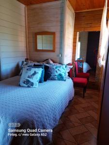 a bedroom with a bed and a red chair at Casa de Sítio Rancho crioulo in Urubici