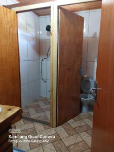 a bathroom with a toilet and a wooden door at Casa de Sítio Rancho crioulo in Urubici