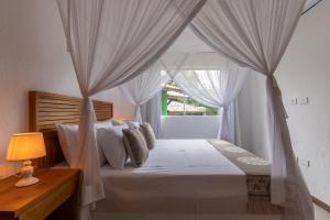 Un dormitorio con una cama con dosel y una ventana. en Trancoso43 - Lindo apartamento 1 suíte , sala com varanda, en Trancoso 62 fotos más