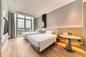 杭州市にあるCourtyard by Marriott Hangzhou Xihuのベッド2台とテーブルが備わるホテルルームです。