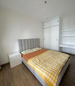 Un dormitorio con una cama con una manta amarilla. en Căn hộ 2pn Vinhomes Grand Park Quận 9 en Gò Công