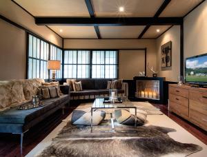 a living room with a couch and a tv at Hakuba Mountain Lodge in Hakuba