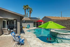 a swimming pool with a green umbrella and two chairs at Coral Beauty! Heated Pool & Spa! in Lake Havasu City
