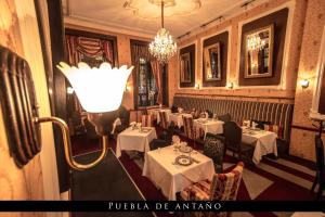 un restaurante con mesas blancas y una luz en la pared en Hotel Puebla de Antaño, en Puebla