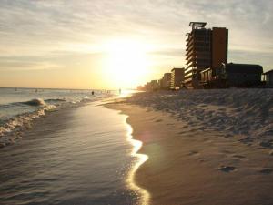 a beach with the sun shining on the sand at McDrifty's Hideaway in Panama City Beach