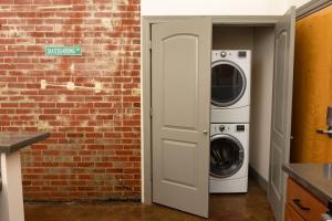 a washer and dryer next to a brick wall at Stunning 2 Br Loft Smack In The Heart Of Downtown in Roanoke